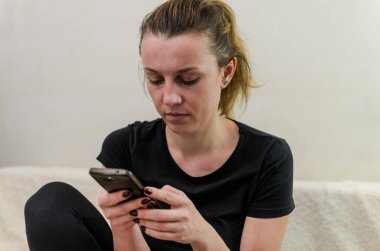 Genç bir kadın akıllı telefondan bir mesaj yazar.