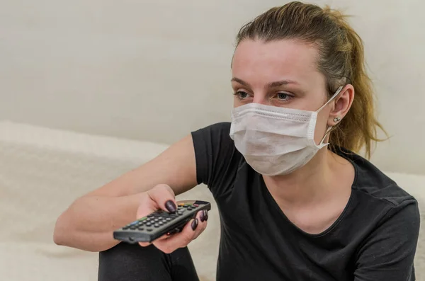 Young Girl Medical Mask Switches Channels Remote Control — Stock Photo, Image