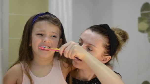若い母親は彼女の娘の子供に彼女の歯を磨く — ストック動画