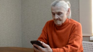 Yaşlı kadın akıllı telefondan mesaj yazıyor.