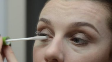 Genç kadın aynada rimel çiziyor.