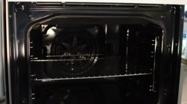 Hizmetçi mikrofiber bezle elektrikli fırını yıkıyor.