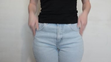 Kot pantolonlu kadın ceplerini boşaltıyor.