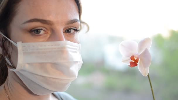 Jovem Máscara Protetora Médica Cheira Uma Flor Orquídea — Vídeo de Stock