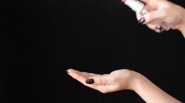 Kadın siyah arka plana antibakteriyel dezenfektan sıkar.