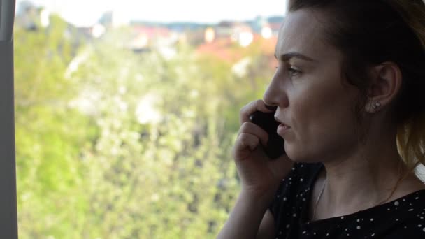年轻女人在窗边打电话 喝着杯子里的咖啡 — 图库视频影像