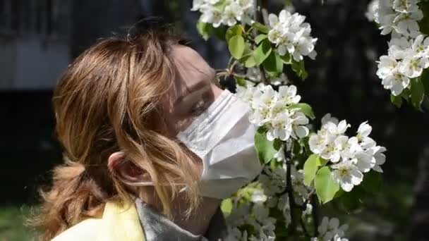 Ung Kvinna Medicinsk Mask Sniffar Körsbär Blommor Solig Dag — Stockvideo