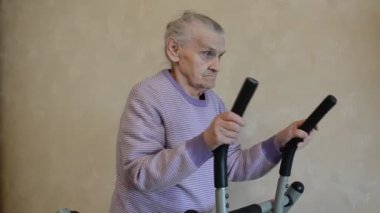 Yaşlı kadın evde eğitim aletleri üzerine eğitim görüyor.