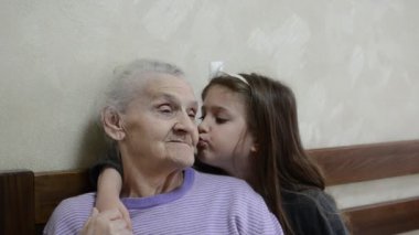 Küçük sevimli kız torun yaşlı bir büyükanneye sarılıyor.