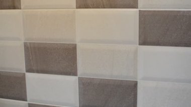 Lastik eldivenli bir hizmetçi duvarda seramik bir fayans yıkıyor.