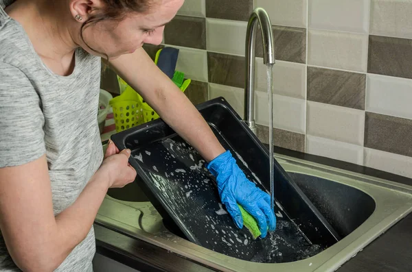 Housekeeper washes a baking dish with dishwashing liquid