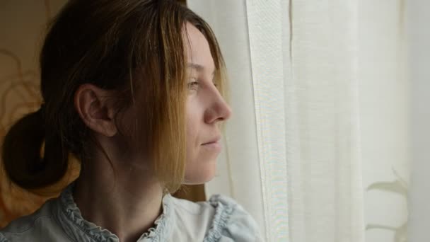 Junge Frau Schaut Durch Die Vorhänge Aus Dem Fenster — Stockvideo