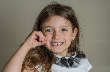 Küçük kız elinde düşmüş süt dişini tutuyor.