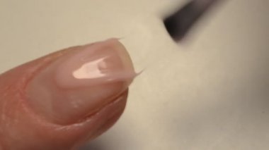 Kadın manikür yaparken ojeyle oje sürüyor.