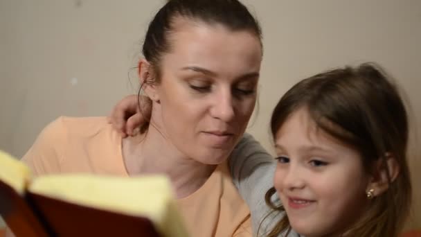 若い母親は娘 幸せな家族に本を読みます — ストック動画
