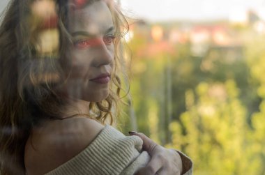 Camdan dışarı bakan genç bir kadın.