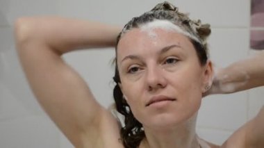 Genç ve çekici kız duşta şampuanı yıkıyor.