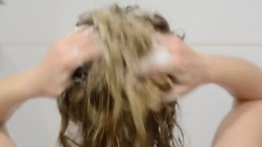 Genç ve çekici kız duşta şampuanı yıkıyor.