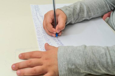 Küçük kız bir kağıt parçasına numara yazmayı öğreniyor.