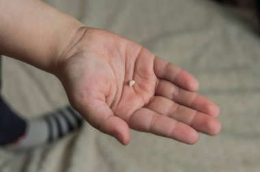 Küçük kız elinde düşmüş süt dişini tutuyor.