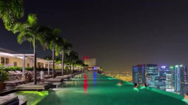 gece ışıklı Singapur ünlü otel çatı katındaki yüzme havuzu panorama 4k zaman atlamalı