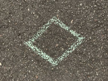 Gri asfalt yola tebeşirle çizilmiş mavi sembol. Yakın plan fotoğraf.