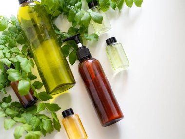 Kozmetik şişe kapları ve beyaz arka planda yeşillik. Doğal organik ürün. Güzellik blogcusu, salon terapisi, markalaşma modeli, minimalizm konsepti. Düz yatıyordu