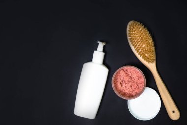 Siyah arka planda vücut fırçası, fırça ve vücut losyonu, sessiz tonlar üst görünüm. Evde kişisel bakım. Refah kavramı.