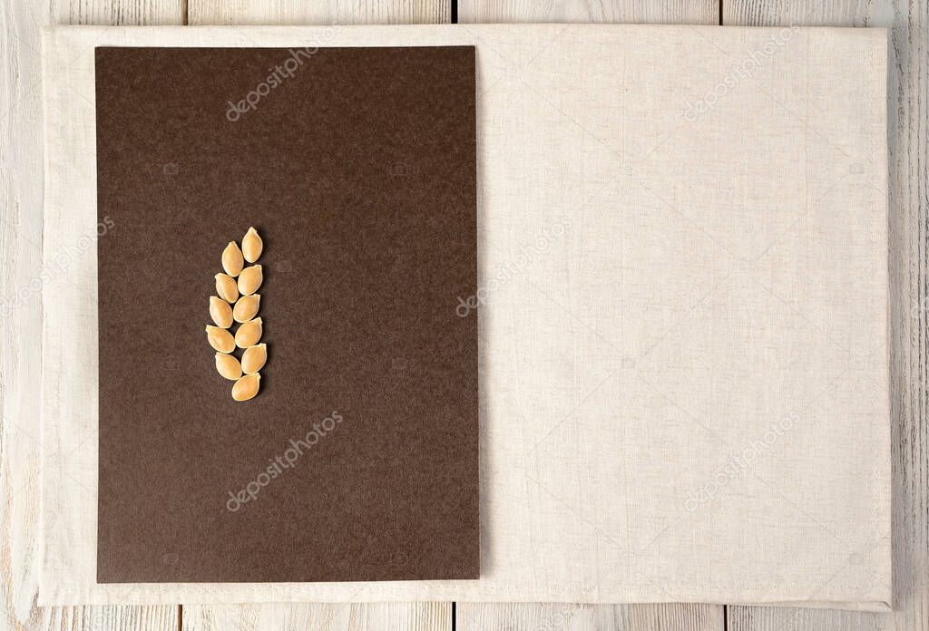 Pumpkin seeds in the form of a spike on a brown-beige background.