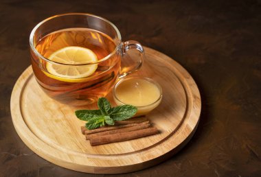 Şeffaf bardakta kokulu siyah çay, nane, tarçın ve bal.