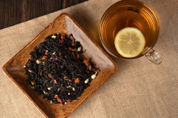 Una taza de té de flores fragantes, limón, menta, canela y una dispersión de té de hojas . — Foto de Stock