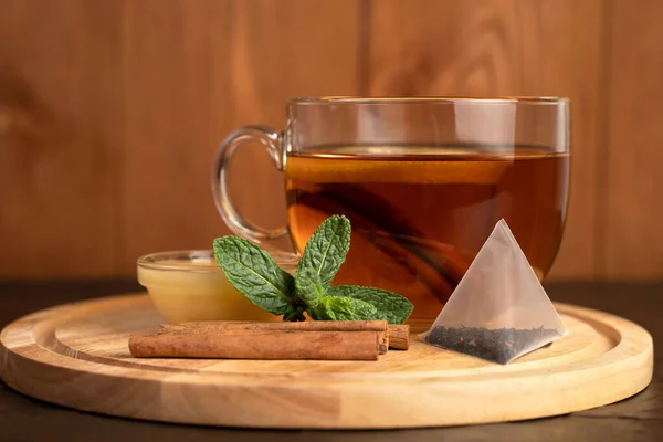 Copo transparente com chá preto perfumado, hortelã e canela e mel . — Fotografia de Stock