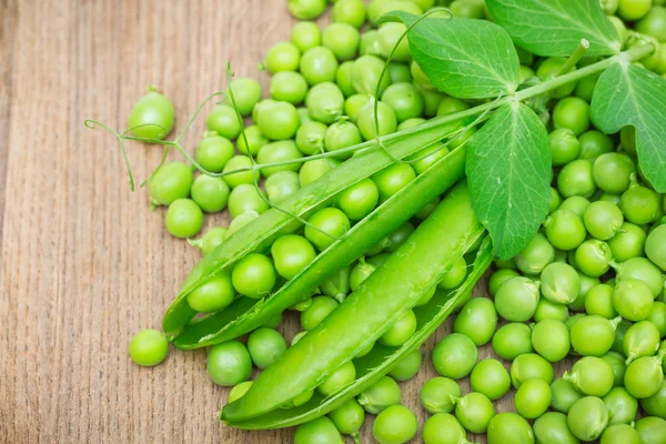 Verse groene erwten op een houten tafel — Stockfoto