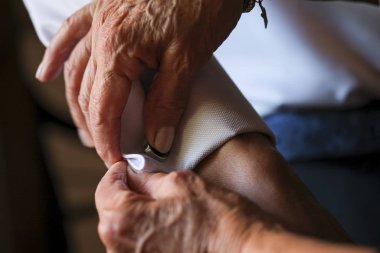 Damadın annesi kol düğmesi ve gömlek takarak hazırlanmasına yardım ediyor.