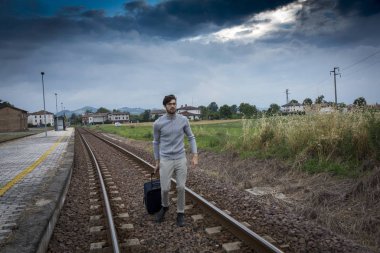 Tren rayları boyunca bavullu bir adam başarısız iş kaybı