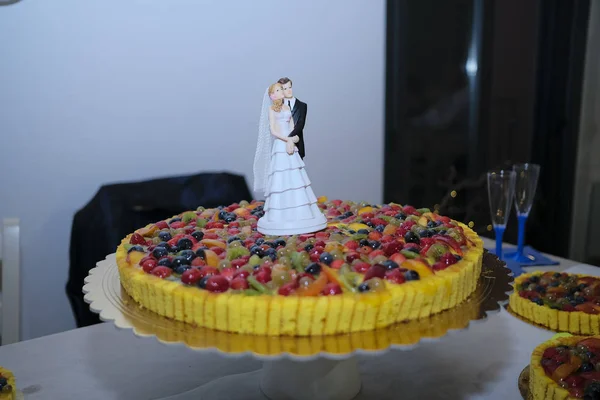 beautiful fruit wedding cake with statue of the bride and groom
