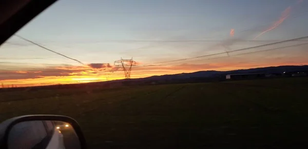 Belo pôr do sol sobre estrada colina verde — Fotografia de Stock