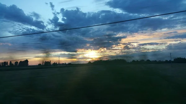 Belo pôr do sol sobre estrada colina verde — Fotografia de Stock