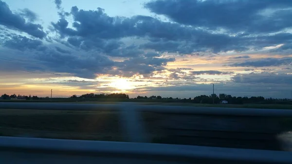 Belo pôr do sol sobre estrada colina verde — Fotografia de Stock