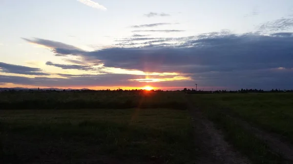 Schöner Sonnenuntergang über der grünen Hügelstraße — Stockfoto