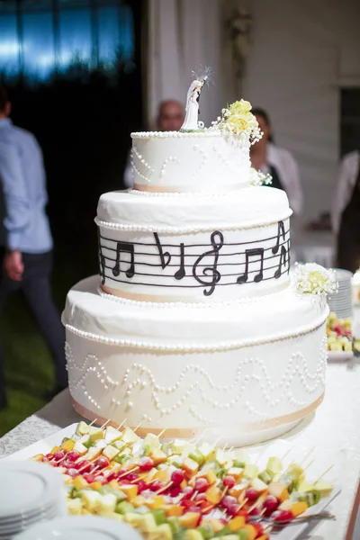 beautiful fruit wedding cake with statue of the bride and groom