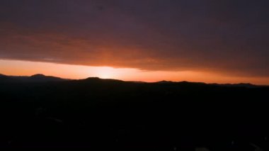 Bulutlu tepelerin ardında güzel bir günbatımı manzarası