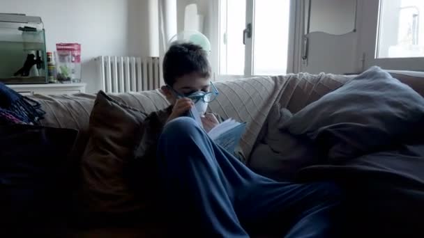 Dziecko włoski chłopiec czyta książkę w domu w czasie wirusa korony — Wideo stockowe