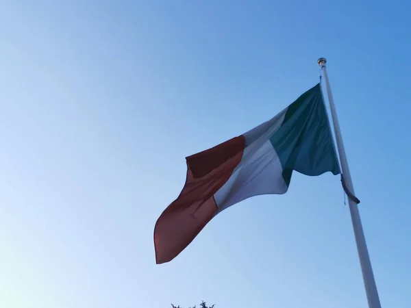 Italská vlajka vlnící se na stožáru za slunečného dne — Stock fotografie