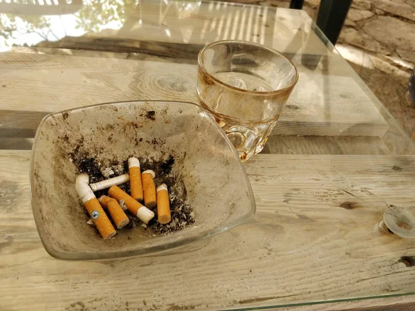 Cinzeiro cheio de cigarros e rabos em uma mesa de bar — Fotografia de Stock