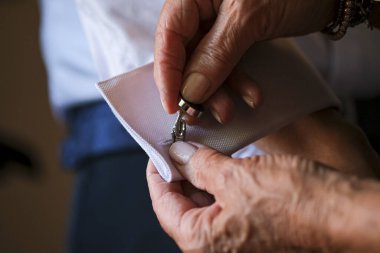 Damadın annesi düğünden önce kelepçeleri ve kol düğmelerini bağlıyor.