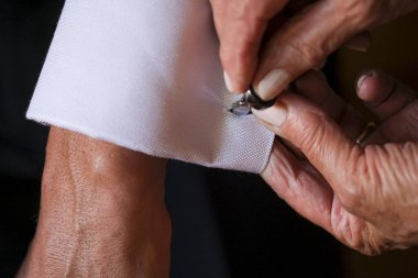 Damadın annesi düğünden önce kelepçeleri ve kol düğmelerini bağlıyor.