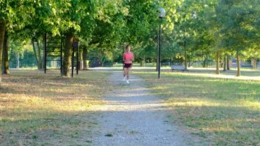 Yaz parkında genç bayan koşucu eğitimi. Spor salonundaki kadın dışarıda koşuyor. Parkta maraton koştuktan sonra nefes alıp veren yorgun kız. Sabah koşusu konsepti