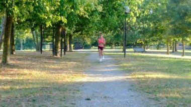 Yaz parkında genç bayan koşucu eğitimi. Spor salonundaki kadın dışarıda koşuyor. Parkta maraton koştuktan sonra nefes alıp veren yorgun kız. Sabah koşusu konsepti