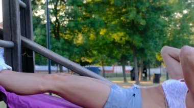 Güzel jimnastikçi kız meyilli bankta mekik çekiyor.